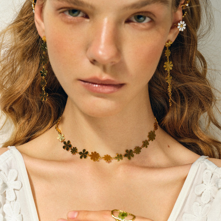 Boucles d'oreilles pendantes asymétriques en acier inoxydable doré, ornées de petites marguerites et d'un pompon élégant.