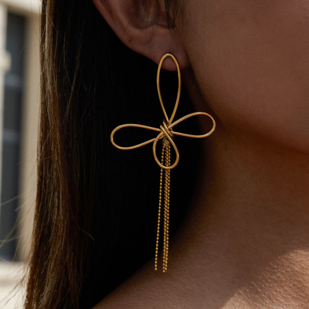 1 paire de magnifiques boucles d'oreilles pendantes pour femme, en acier inoxydable doré, avec nœud papillon et pompon.